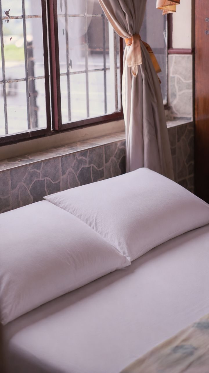 Almohadas y sábanas blancas junto a la ventana