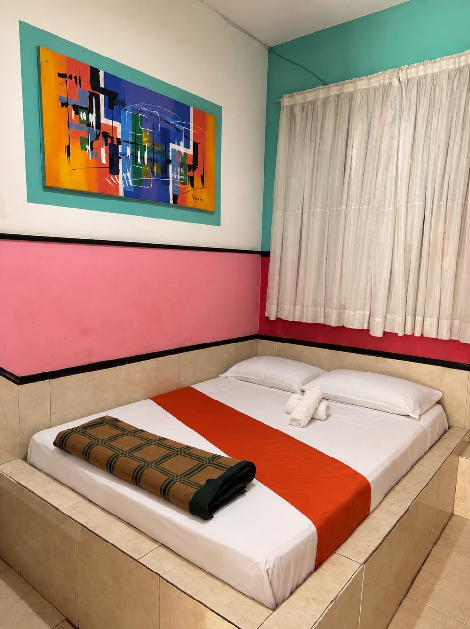 Habitación Matrimonial Sencilla con cama matrimonial, camino naranja y toallas enrolladas